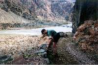 Ron removes a stone from his shoe.  Silver Bridge in background.
